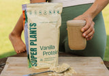 Woman with protein smoothie in bright kitchen, Vanilla Protein jar, Protein banana spinach smoothie, Woman stable energy working, Vanilla Protein ingredients
